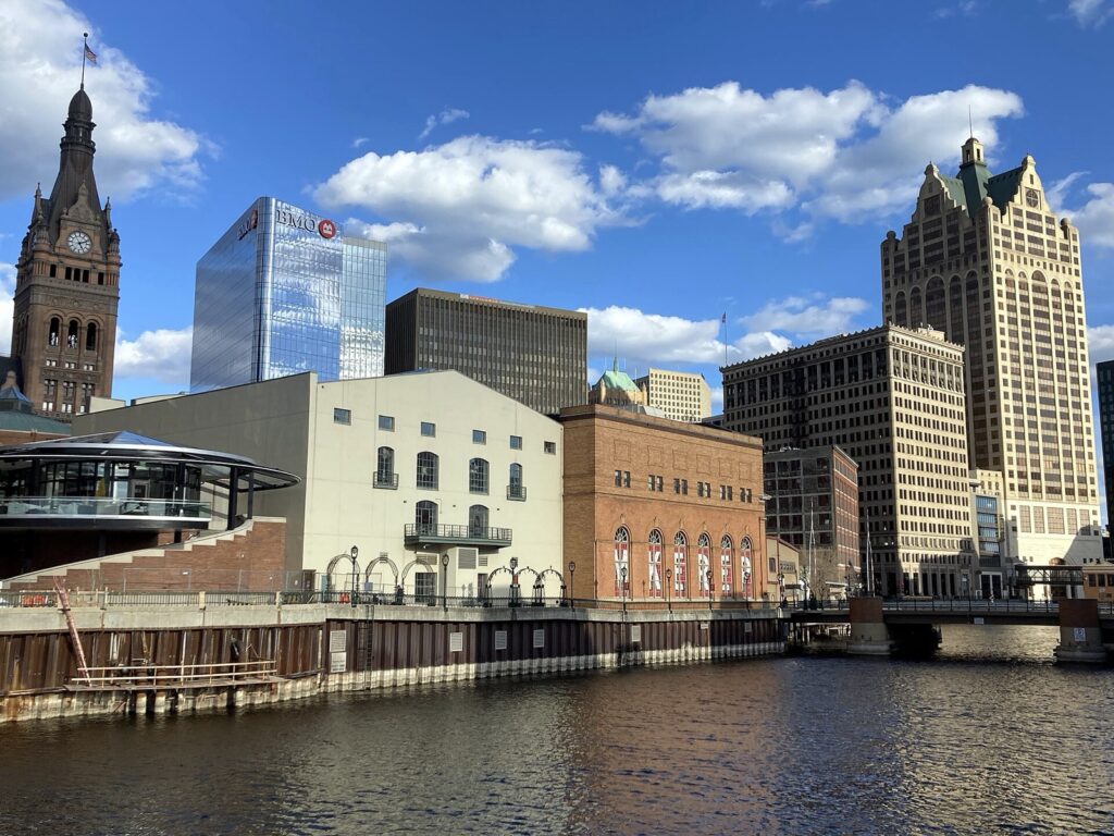 Downtown Milwaukee buildings and clock tower along the Milwaukee River on a sunny day